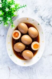Marinated eggs served on an oval plate with savory sauce.